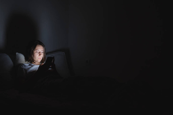 Woman in bed uses phone late at night.  - Foto, Imagen
