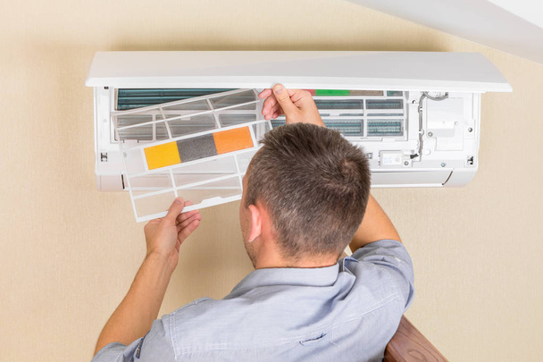 Male technician cleaning air conditioner indoors - Foto, Imagen