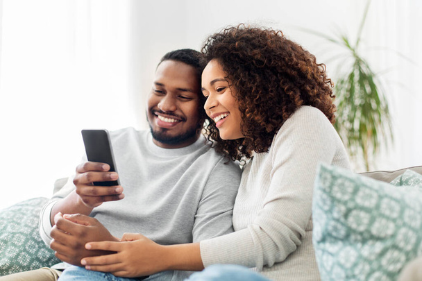 africký americký pár s chytrým telefonem doma - Fotografie, Obrázek