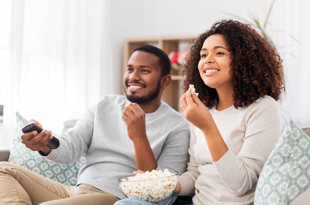 african couple with popcorn watching tv at home - Photo, Image
