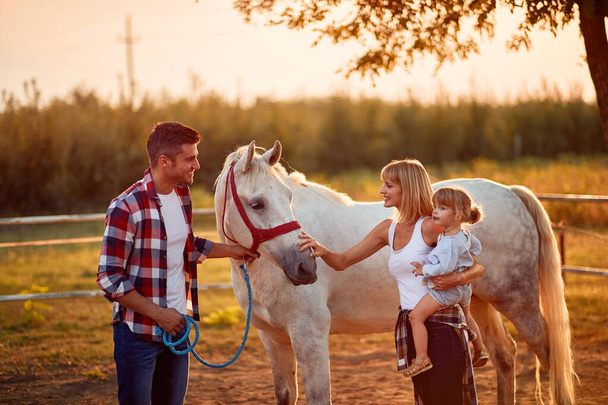 happy family in a horse farm petting horses  - Photo, Image