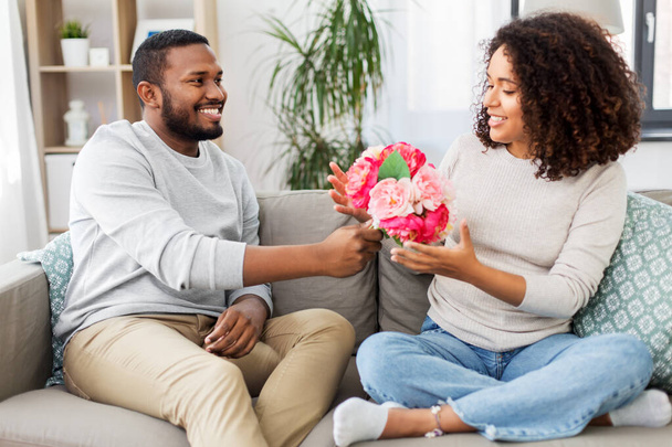happy couple with bunch of flowers at home - Foto, Bild