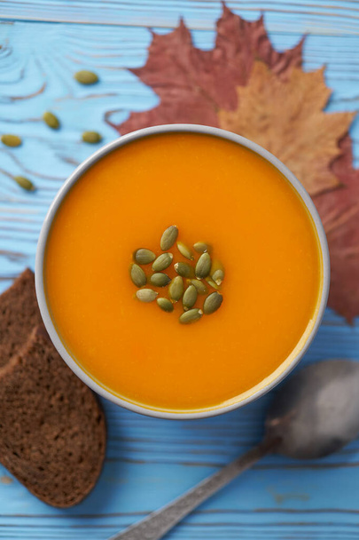 Pumpkin and carrot puree soup decorated with seeds. Blue wooden background, autumn composition, top view. - Photo, Image
