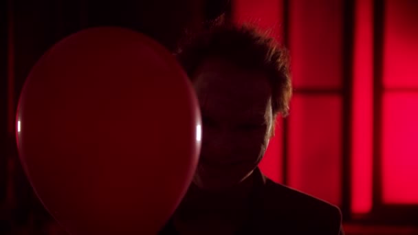 Un payaso asustadizo asomándose desde el globo rojo y sonriendo espeluznante parpadeando la luz
 - Imágenes, Vídeo