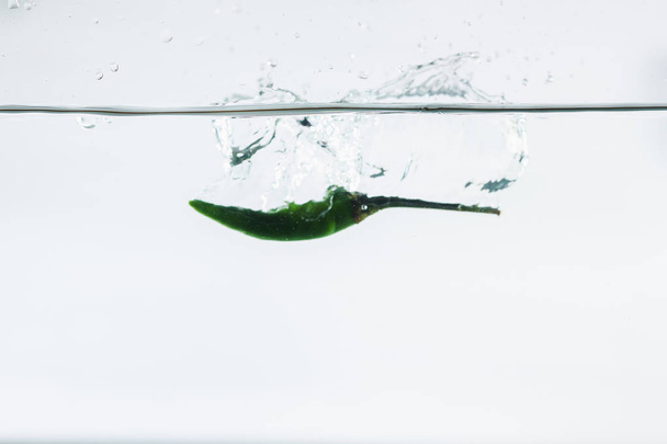 πράσινο τσίλι, πιτσιλιές νερού, διαλυμένες σε λευκό φόντο - Φωτογραφία, εικόνα