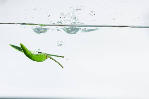 green chilli, water splashes, solated on a white background - Foto, afbeelding