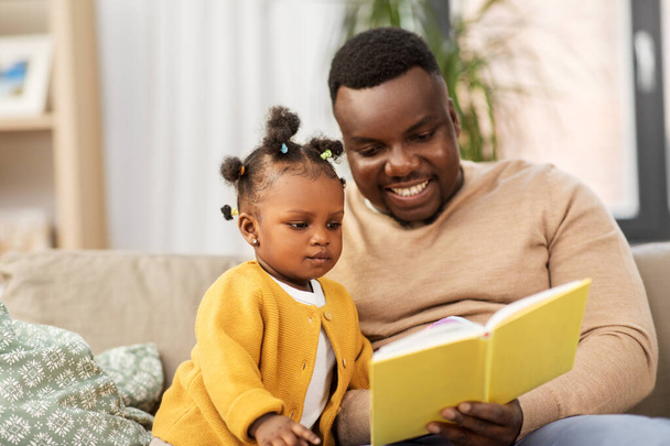 african father reading book for baby daughter - 写真・画像