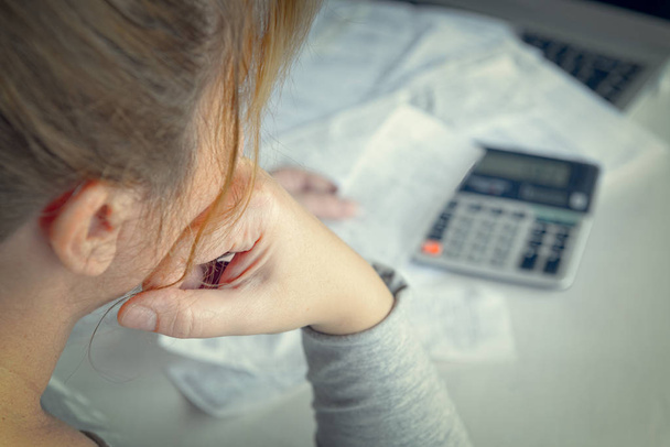 Женщина использует калькулятор для подведения итогов расходов на дому
 - Фото, изображение