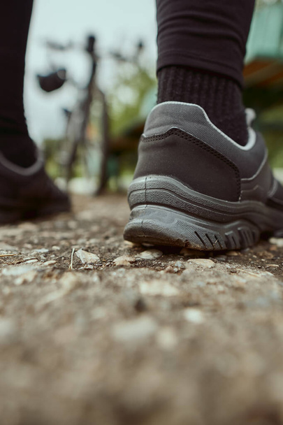 Close-up of the legs of a man in sneakers on the background of a bicycle - Foto, Bild