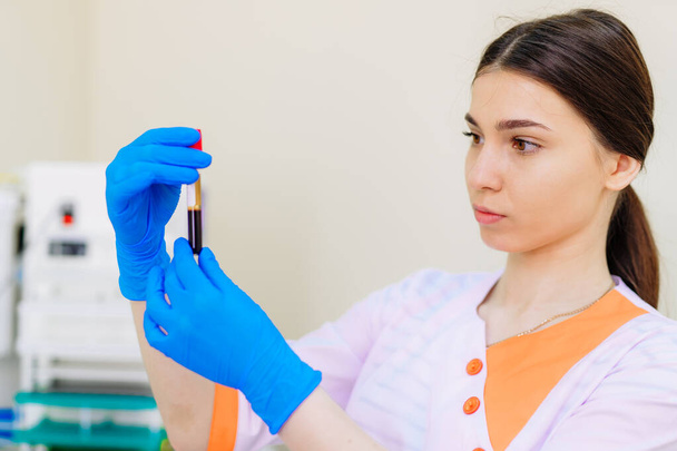 Portrait of pretty female laboratory assistant analyzing a blood sample at hospital - Fotoğraf, Görsel