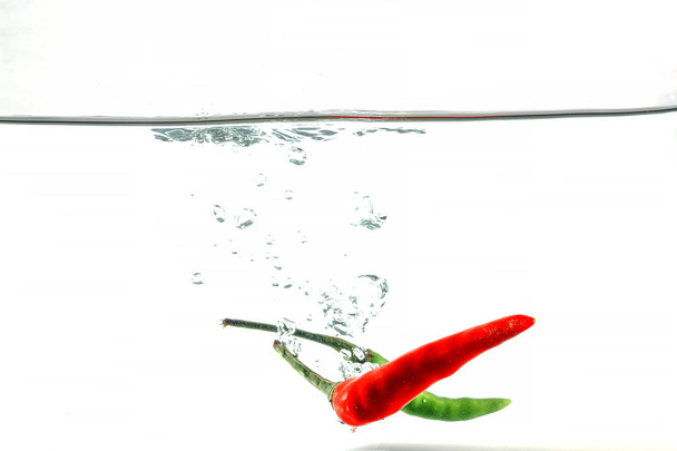 Peperoncino rosso, spruzzi d'acqua, solato su fondo bianco
 - Foto, immagini