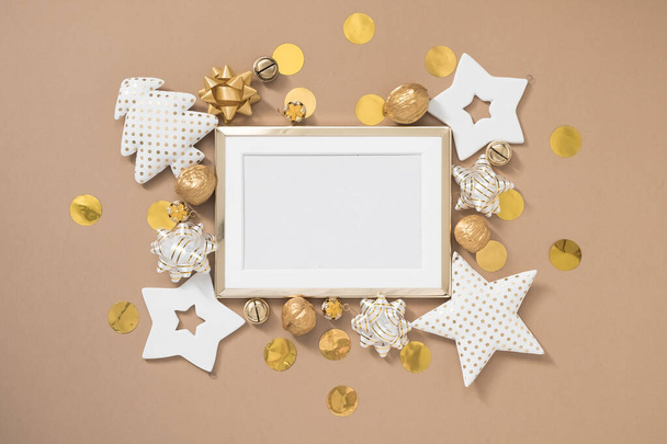 Christmas golden frame with white and golden decorations on pastel beige background. Flat lay, top view, copy space - 写真・画像
