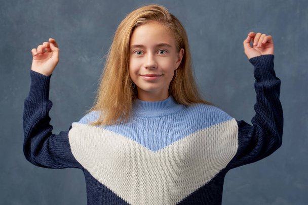 Teenage girl blonde in warm sweater isolated wall - Фото, зображення