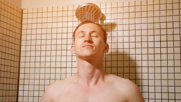 Retrato de un joven tomando una ducha peinándose los pelos con las manos
. - Foto, imagen