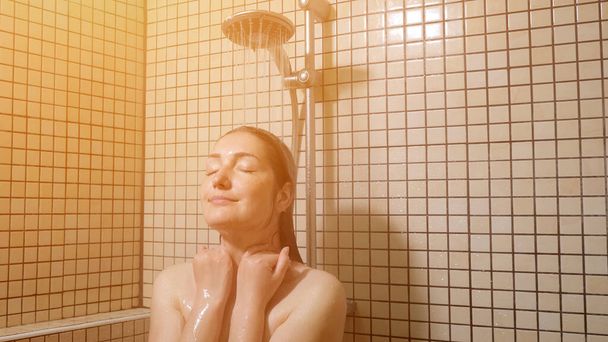 Brunette femme aux cheveux longs prend une douche
 - Photo, image