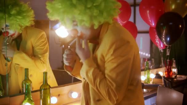 ein müder Clown zündet sich nach der Arbeit die Zigarette in der Umkleidekabine an - reißt sich Perücke und falsche rote Nase ab - Filmmaterial, Video