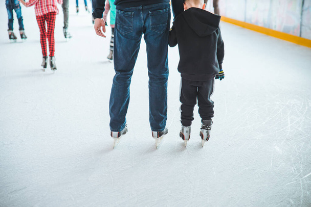 LVIV, UKRAINE - February 3, 2019: father teaching son how to skate on ski rink - Photo, Image