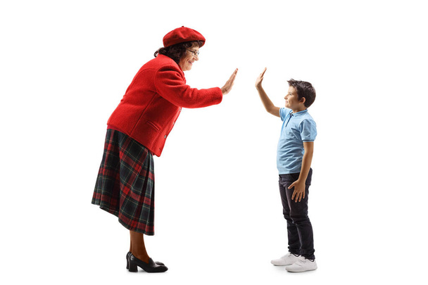 Eedlerly lady gesturing high-five with a young boy - Фото, зображення