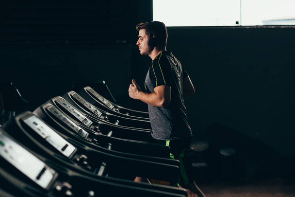 Lonely man running on treadmill at the gym - Photo, Image