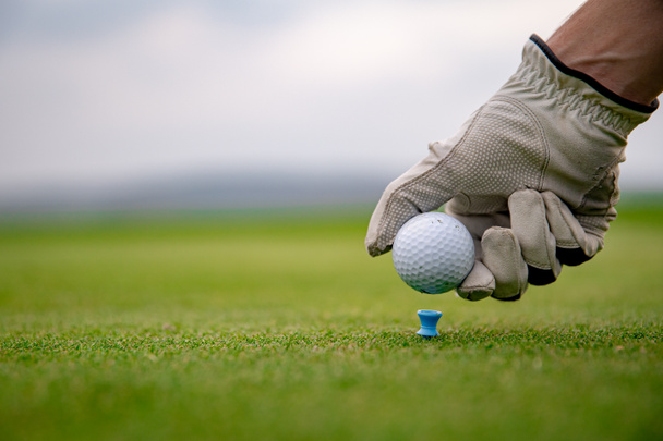 A golfozó előkészíti a labdát, hogy lőjenek a golfpályára. - Fotó, kép