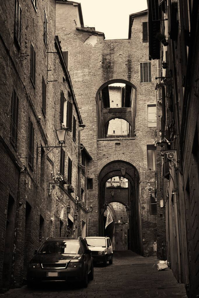 Вуличний вид зі старими будинками та аркою в Сієні (Італія).. - Фото, зображення