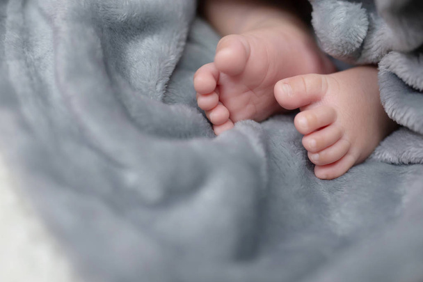 Close up Pés de bebê recém-nascido pequeno adorável rosa nua minúsculo com vestindo calças, vestidos de tricô. Pequena criança com bonito no lençol Lã macia no cobertor branco, vista acima. Espaço para SMS. foco suave
. - Foto, Imagem