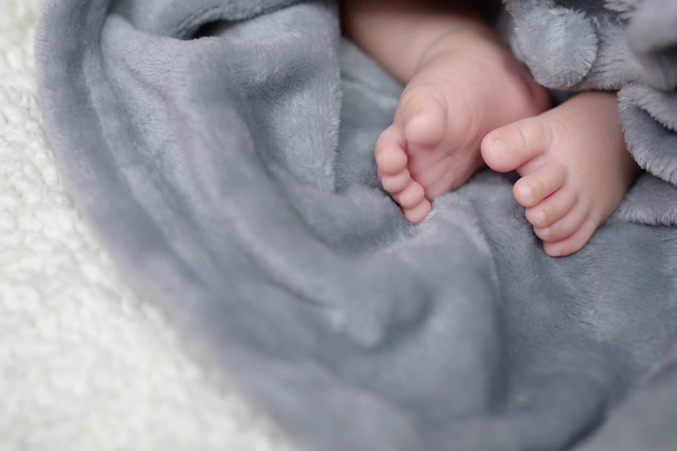 Κοντινό πλάνο νεογέννητα πόδια του μωρού μικρό μικροσκοπικό αξιολάτρευτο γυμνό ροζ με παντελόνι, πλεκτά φορέματα. Μικρό βρέφος με χαριτωμένο σε σεντόνι Μαλακό μαλλί σε λευκή κουβέρτα, πάνω από την προβολή. Χώρος για κείμενο. μαλακή εστίαση. - Φωτογραφία, εικόνα