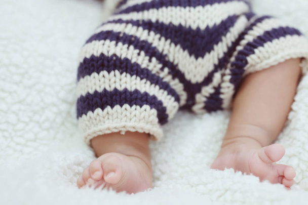 Close up Newborn baby feet small tiny adorable bare pink. Little infant with cute on bed sheet sleep on grey blanket, above view. Space for text. soft focus. - Photo, Image