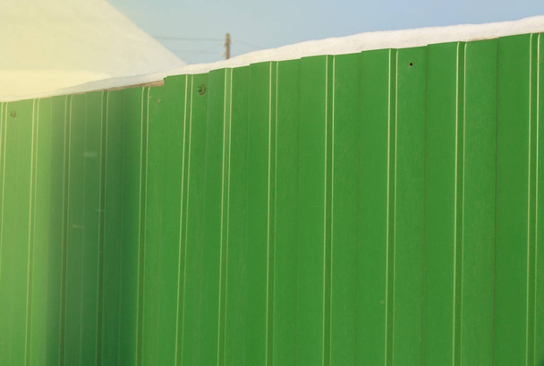 Modern green metal corrugated siding fence, outdoor winter space, safety and security, veneer texture - Photo, Image