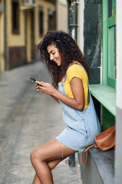 Young Arab girl looking at her smart phone outdoors - Φωτογραφία, εικόνα