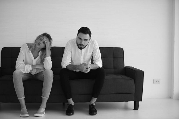 Monochromes Foto eines jungen Paares, das während eines Streits auf dem Sofa sitzt  - Foto, Bild