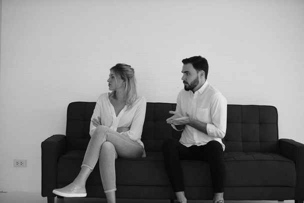 monochromatyczne zdjęcie młodej pary siedzącej na kanapie podczas kłótni mężczyzny z kobietą - Zdjęcie, obraz