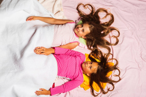 Childhood and morning concept. Kids in pink pajamas - Фото, изображение