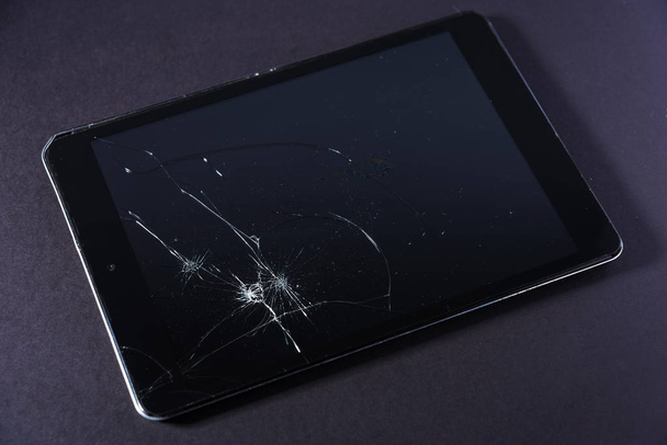 Beeld met gebroken weergave van een smartphone of tablet computer op zwarte achtergrond. - Foto, afbeelding
