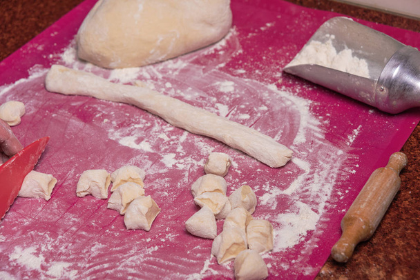 Ruoanlaitto keittiössä Ukrainan kansallisen lautasen käyttäen valkoisia jauhoja taikina ja raejuusto täyte ja keitettyjä perunoita. Varenikit
. - Valokuva, kuva