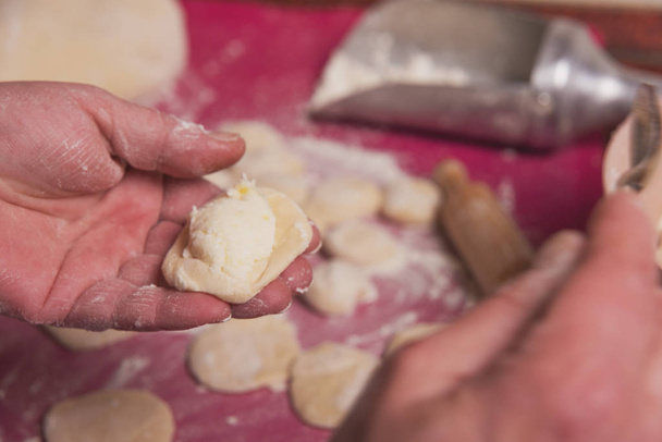 白小麦粉生地とカッテージチーズ詰め物とゆでたジャガイモを使用して、ウクライナの国民料理のキッチンで料理.ヴァレリックス. - 写真・画像