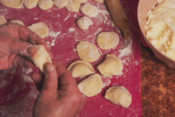 Vaření v kuchyni ukrajinského národního pokrmu s použitím těsta z bílé mouky a tvarohové nádivky a vařených brambor. Varenici. - Fotografie, Obrázek