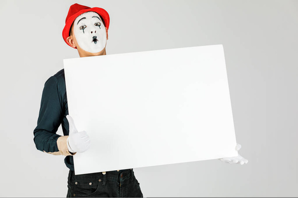 feliz artista MIME sosteniendo una pizarra blanca en blanco, sobre un fondo blanco
 - Foto, imagen