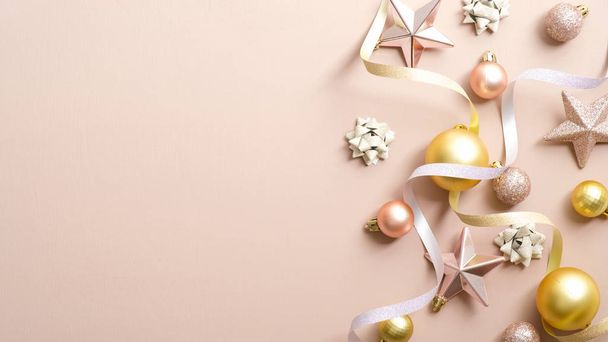 Christmas greeting card mockup with elegant decorations, gold Xmas balls, pink stars, ribbon on pastel ivory background. Happy New Year banner template with copy space, Christmas party invitation. - Zdjęcie, obraz