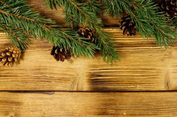 Рождественская композиция с елочными ветвями и конусами на деревянном фоне. Вид сверху, пространство для копирования - Фото, изображение