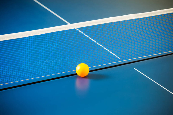 Empty blue table with a net and a yellow ball - Foto, Bild