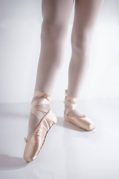 Beine und Füße mit rosa Satin-Spitzenschuhen von einer klassischen Tänzerin - Foto, Bild
