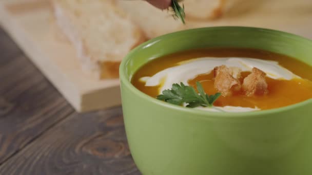 Krémes sütőtök leves főzés. Séf díszíti krémes sütőtök leves egy zöld tál gyógynövények. Közelről. 4k. - Felvétel, videó