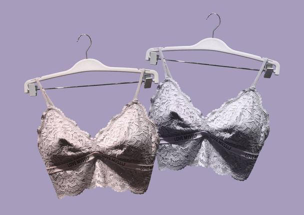 Lace bras on a hanger isolated on purple background. Textile, Underwear. Vintage Lace Bras unlined lace detailing. Sexuality lingerie. Fashion concept. Stylish lingerie. Set of female underwear. Pattern - Photo, Image