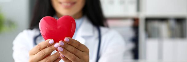Cardiolog feminino segurando nos braços vermelho brinquedo coração
 - Foto, Imagem