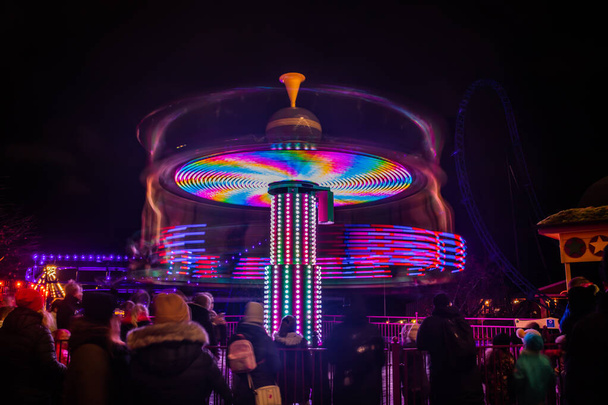 Un carrusel colorido borroso en movimiento en el parque de atracciones, iluminación nocturna. Larga exposición
. - Foto, imagen
