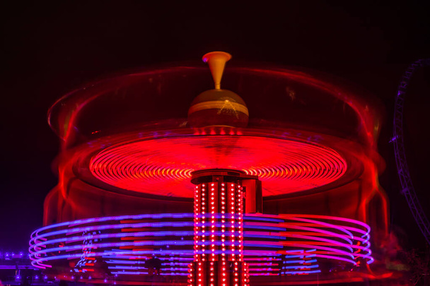 Un carrousel coloré flou en mouvement au parc d'attractions, illumination nocturne. Longue exposition
. - Photo, image