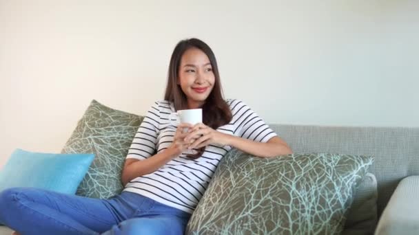 footage of beautiful asian woman spending time alone at home with cup of hot coffee - Felvétel, videó