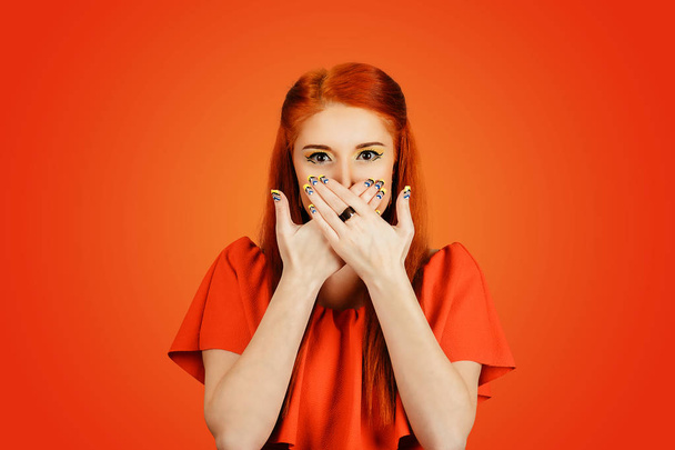 Woman holds her hands to her mouth, she shows silence, red background - Foto, Imagem