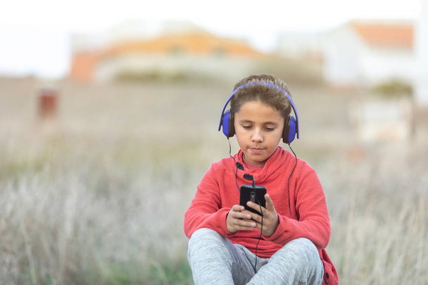 Enfant aux cheveux foncés écoutant de la musique avec des hadphones bleus et un m
 - Photo, image